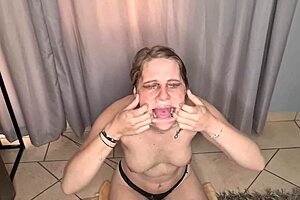 A pale girl toplessly gags on dildo with collected spit smeared on face