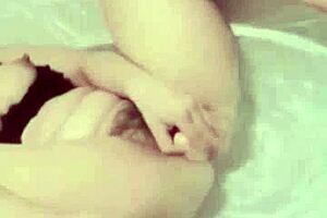 This Asian girl is masturbating in the bathroom with a dildo while watching porn.