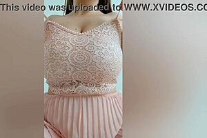 A beautiful girl with brown hair wears a pink dress and enjoys playing with her big natural tits.
