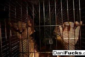 Dani Daniels teases with her big tits while masturbating in a cage.