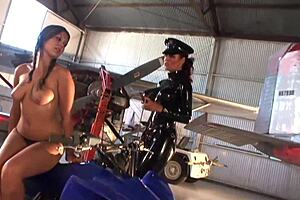 Two lesbian friends lick big tits and asses with strap on in warehouse