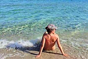 Young European nudist enjoying public beach in a natural way