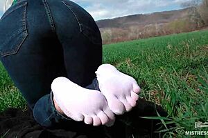 Goddess feet in white socks and jeans on spring grass