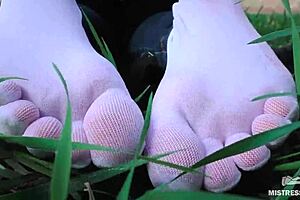 Goddess feet in white socks and jeans on spring grass