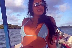 Latina woman in bikini sunbathes on the deck of a boat with her husband