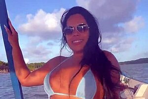 Latina woman in bikini sunbathes on the deck of a boat with her husband