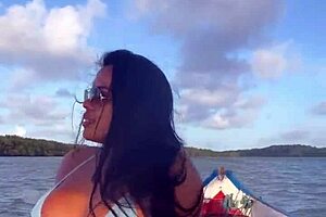 Latina woman in bikini sunbathes on the deck of a boat with her husband