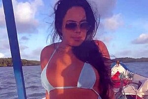 Latina woman in bikini sunbathes on the deck of a boat with her husband