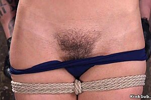 Hairy beauty in hogtie receives caning.